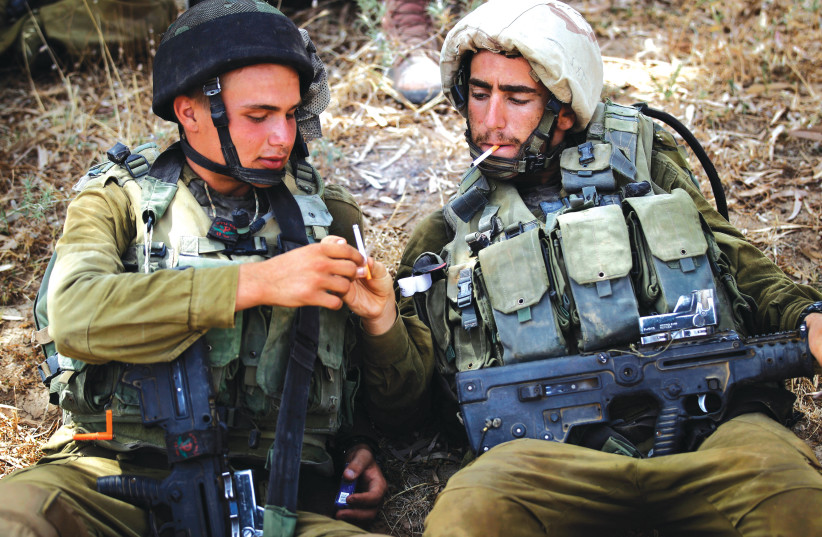  NAHAL SOLDIERS share cigarettes near the Gaza Strip. ‘We know from the world that not everyone will stop smoking – probably only 3%-4%. If 4% of the 7,000 people who die yearly from smoking are saved, that is already 300 people per year,’ says Dr. Gary Ginsberg.  (photo credit: FINBARR O'REILLY / REUTERS)