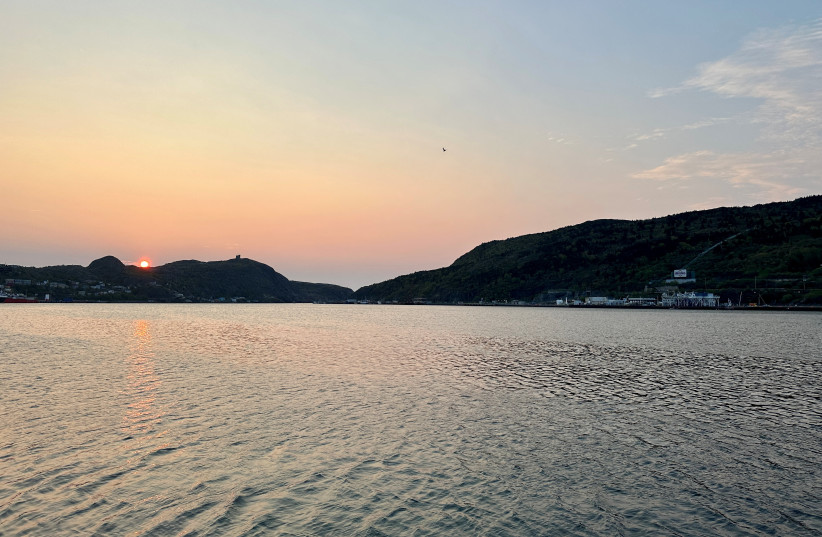 The sun rises as the search for the missing OceanGate Expeditions submersible, which is carrying five people to explore the wreck of the sunken Titanic, enters its final hours, over St. John?s Harbour, Newfoundland and Labrador, Canada, June 22, 2023. (photo credit: REUTERS/ERIC COX)