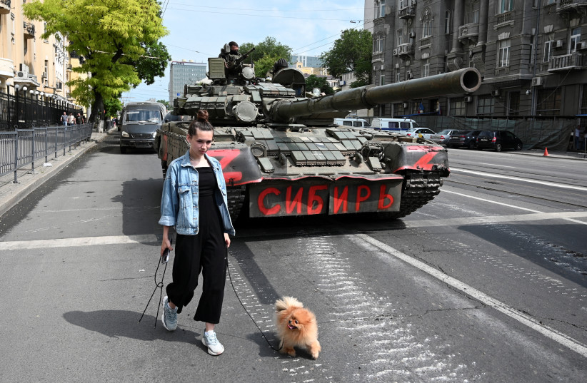  A woman with a dog walks past a tank as fighters of Wagner private mercenary group are deployed in a street near the headquarters of the Southern Military District in the city of Rostov-on-Don, Russia, June 24, 2023. A sign on a tank reads: "Siberia". (photo credit: REUTERS/STRINGER)