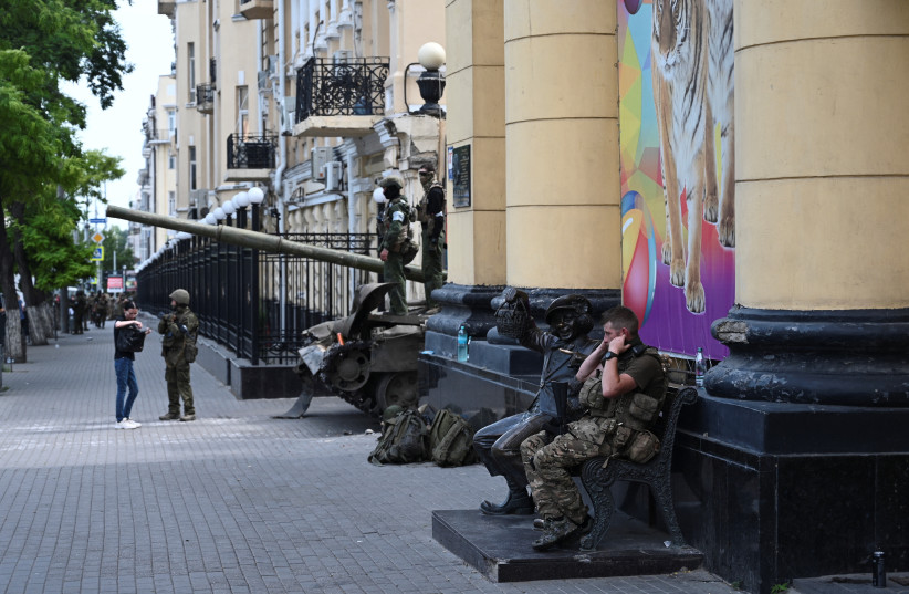 A fighter of Wagner private mercenary group sits on a bench outside a local circus near the headquarters of the Southern Military District controlled by Wagner fighters in the city of Rostov-on-Don, Russia, June 24, 2023. (photo credit: STRINGER/ REUTERS)