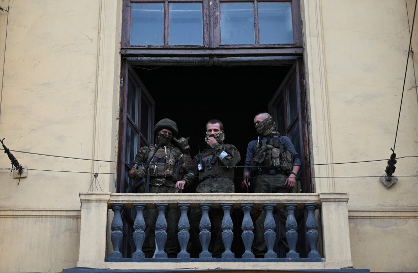 Fighters of Wagner private mercenary group stand on a balcony while being deployed at the headquarters of the Southern Military District in the city of Rostov-on-Don, Russia, June 24, 2023.  (photo credit: STRINGER/ REUTERS)