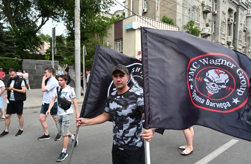 A supporter of Wagner private mercenary group holds flags near the headquarters of the Southern Military District controlled by Wagner fighters in the city of Rostov-on-Don, Russia, June 24, 2023. (photo credit: STRINGER/ REUTERS)