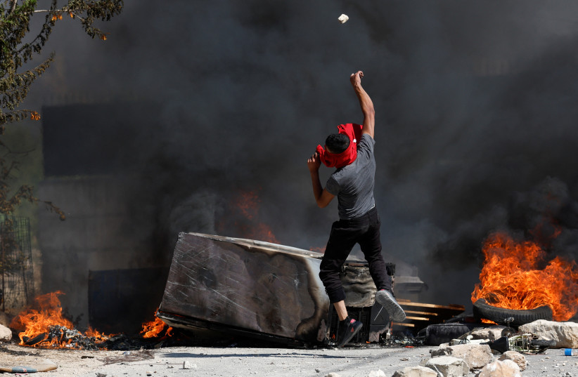  A Palestinian throws a stone during clashes with Israeli troops after Israeli settlers attack Umm Safa village near Ramallah, in the West Bank, June 24, 2023 (photo credit: REUTERS/MOHAMAD TOROKMAN)