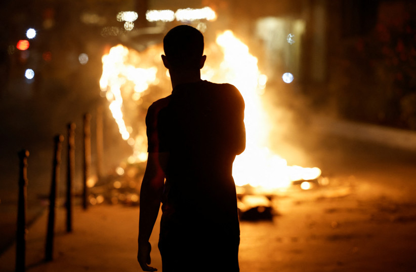  A person stands near a burning container as people protest following the death of Nahel, a 17-year-old teenager killed by a French police officer in Nanterre during a traffic stop, and against police violence, in Paris, France, June 30, 2023 (photo credit: REUTERS/JUAN MEDINA)