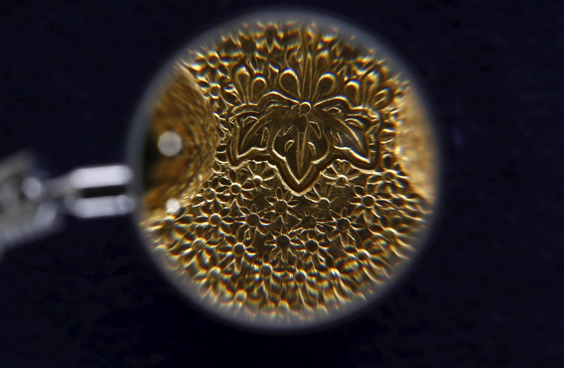 A detail of the engraving on a Japanese gold ingot that was in use between the 16th and 17th centuries is seen enlarged under a magnifying glass, at the Currency Museum of the Bank of Japan in Tokyo, November 18, 2015. Picture taken November 18, 2015. (photo credit: THOMAS PETER/REUTERS)