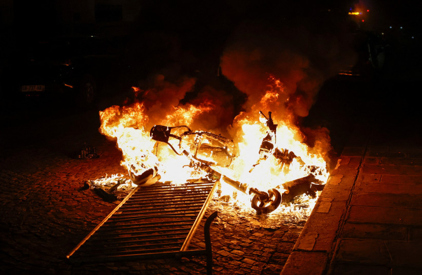  A burning motorbike is seen during the fifth day of protests following the death of Nahel, a 17-year-old teenager killed by a French police officer in Nanterre during a traffic stop, in Paris, France, July 2, 2023. (photo credit: REUTERS/JUAN MEDINA)