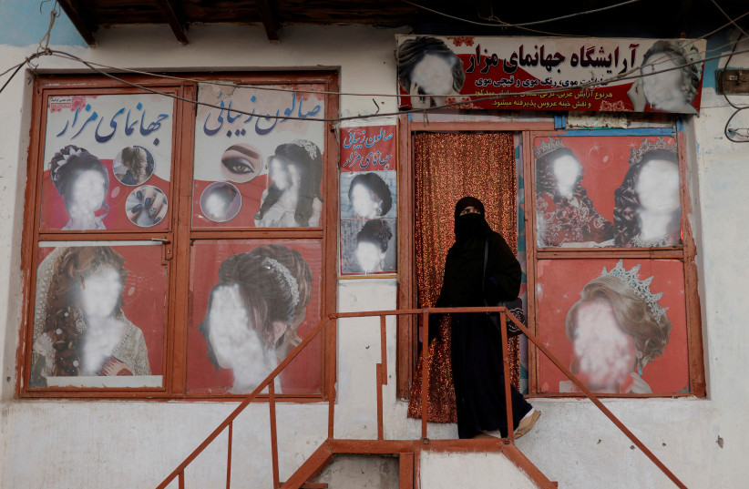  A woman wearing a niqab enters a beauty salon where the ads of women have been defaced by a shopkeeper in Kabul, Afghanistan October 6, 2021. (photo credit: REUTERS/JORGE SILVA/FILE PHOTO)
