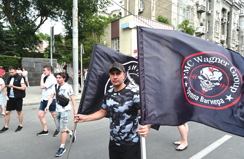  A SUPPORTER of the Wagner private mercenary group holds flags near the headquarters of the Wagner fighter-controlled Southern Military District in the city of Rostov-on-Don, Russia, last month (photo credit: REUTERS)