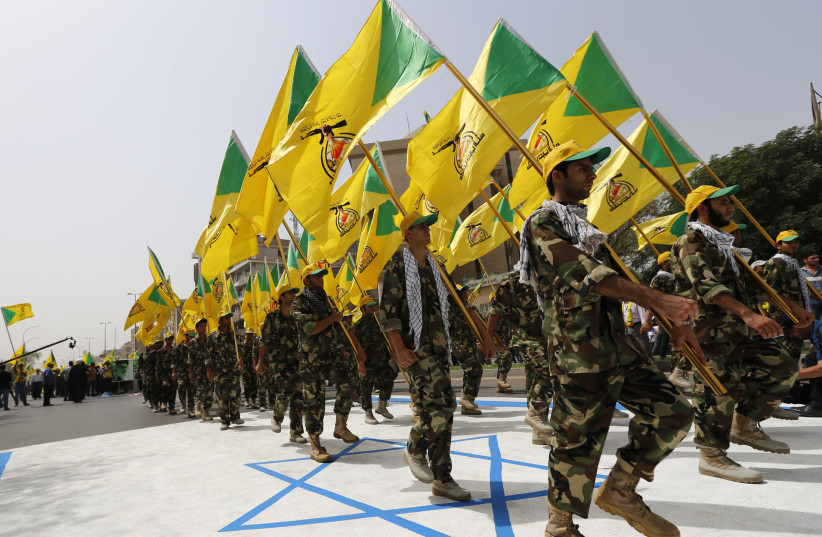  Iraqi Shi'ite Muslim men from the Iranian-backed group Kataib Hezbollah wave the party's flags as they walk along a street painted in the colours of the Israeli flag during a parade marking the annual Quds Day, or Jerusalem Day, on the last Friday of Ramadan, in Baghdad. July 25, 2014 (photo credit: THAIER AL-SUDANI/REUTERS)