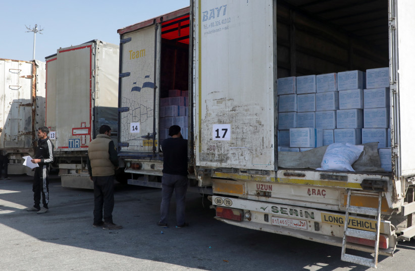 Men inspect trucks carrying aid from UN World Food Programme (WFP), following a deadly earthquake, at Bab al-Hawa crossing, Syria February 20, 2023. (photo credit: REUTERS/MAHMOUD HASSANO)
