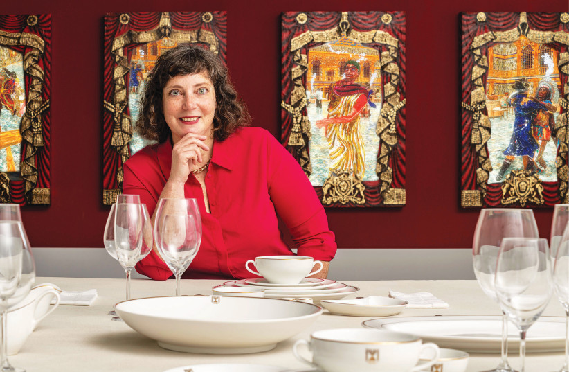  NURIT GOSHEN, curator of Chalcolithic and Bronze Age archaeology at the Israel Museum and curator of The Feast exhibit poses with a set of formal Israeli Foreign Ministry dinnerware displayed at the exhibit. (photo credit: Elie Posner/Israel Museum)