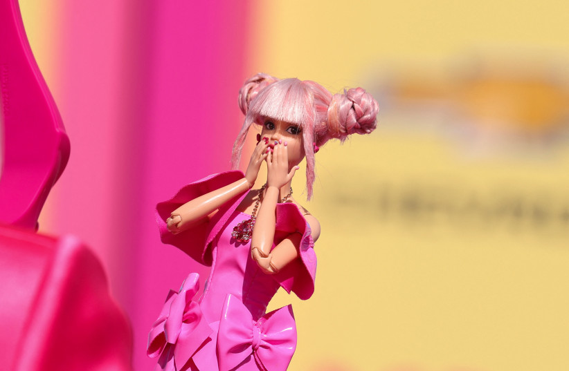 A fan takes a photo of a Barbie doll at the world premiere of the film "Barbie" in Los Angeles, California, U.S., July 9, 2023 (photo credit: MIKE BLAKE/REUTERS)
