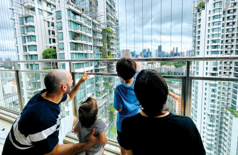  Israeli ex-pat Atar Sandler and her husband and children overlook the skyline of the financial hub from their Singapore apartment balcony, last year.  (photo credit: CHEN LIN/REUTERS)