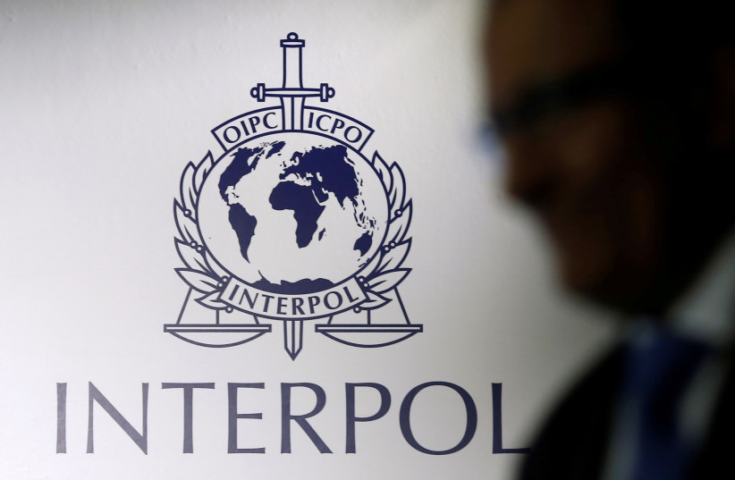  A man passes an Interpol logo during the handing over ceremony of the new premises for Interpol's Global Complex for Innovation, a research and development facility. (photo credit: REUTERS/EDGAR SU/FILE PHOTO)