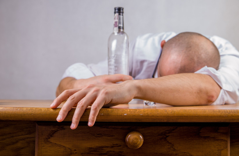  An illustrative image of a man drunk and passed out while holding a bottle of alcohol. (photo credit: PXHERE)