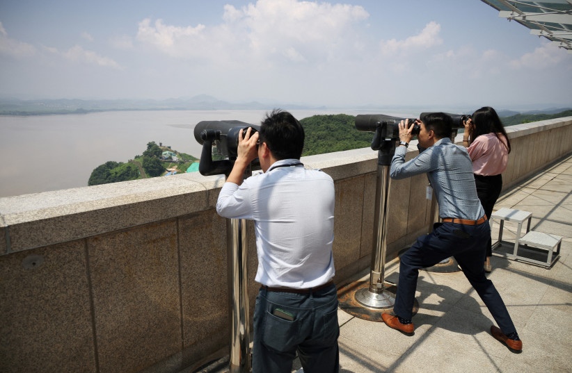 People look at North Korea territory through a pair of binoculars at an observation platform near the demilitarized zone separating the two Koreas, in Paju, South Korea July 19, 2023 (photo credit: REUTERS/KIM HONG-JI/FILE PHOTO)