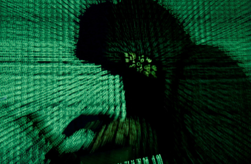 A man holds a laptop computer as cyber code is projected on him in this illustration picture taken on May 13, 2017. (photo credit: KACPER PEMPEL/ILLUSTRATION PHOTO/REUTERS)