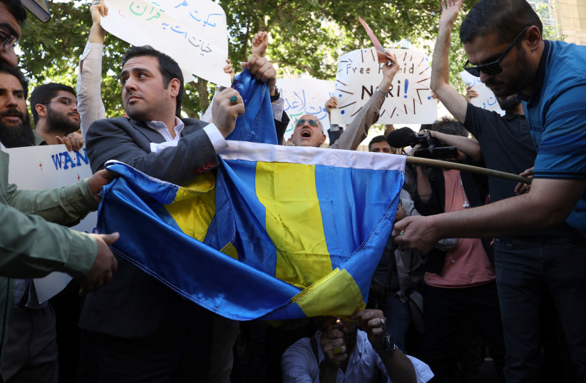  Demonstrators burn the Swedish flag during a protest against a man who burned a copy of the Quran outside a mosque in the Swedish capital Stockholm, in front of the Swedish Embassy in Tehran, Iran June 30, 2023 (photo credit: MAJID ASGARIPOUR/WANA)