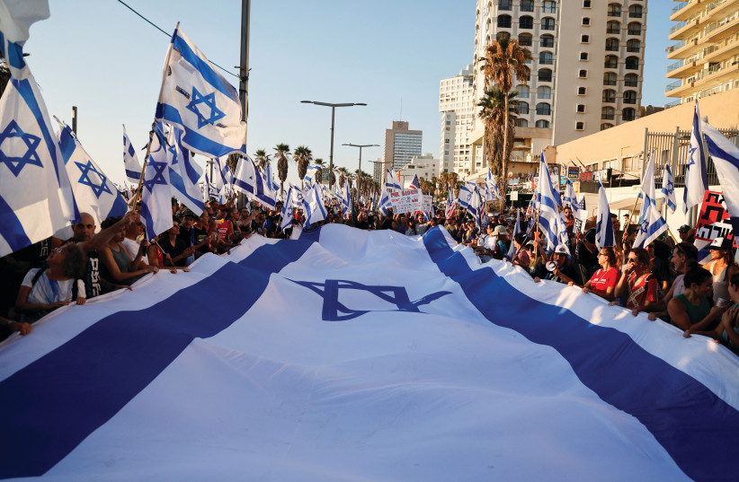  PEOPLE HOLD a gigantic Israeli flag as they demonstrate on Tuesday’s Day of Disruption, near the US consulate in Tel Aviv (photo credit: AMMAR AWAD/REUTERS)