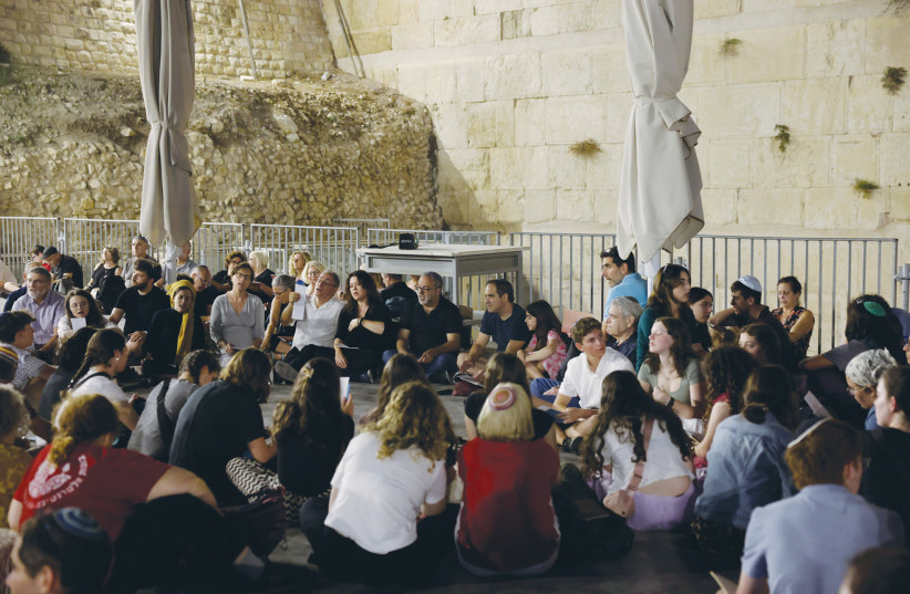  MEN, WOMEN, and children sit at the Ezrat Yisrael section of the Western Wall Wednesday night to read Eicha (the Book of Lamentations) at the start of the Tisha Be’av fast. (photo credit: MARC ISRAEL SELLEM/THE JERUSALEM POST)