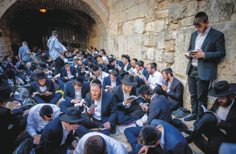  WORSHIPERS SIT on the ground at the Little Western Wall, mourning on Tisha Be’av, last Thursday. ‘On Tisha Be’av I contemplate whether we, as Jews, were responsible through our actions or inactions for our own fate,’ says the writer.  (photo credit: Chaim Goldberg/Flash90)