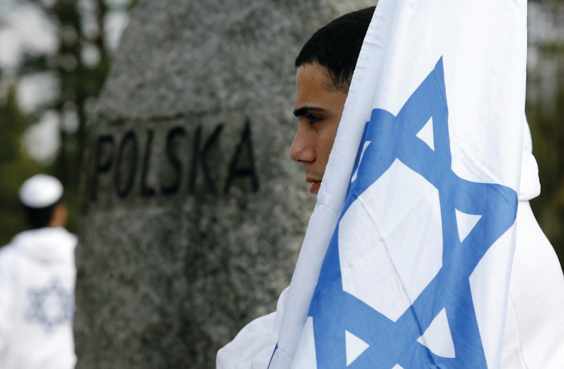  AN ISRAELI youth holds a flag in front of memorial stones at the Treblinka Nazi Death Camp memorial, eastern Poland.  (photo credit: KACPER PEMPEL/REUTERS)