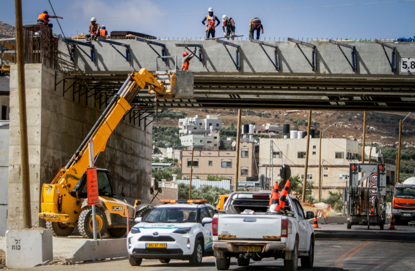 Israeli and Palestinian workers work on a new bridge in the town Hawara, south of the West Bank city of Nablus, July 10, 2023 (photo credit: NASSER ISHTAYEH/FLASH90)