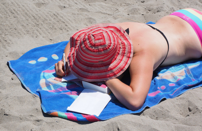  A woman is seen tanning at the beach (Illustrative). (photo credit: PXHERE)