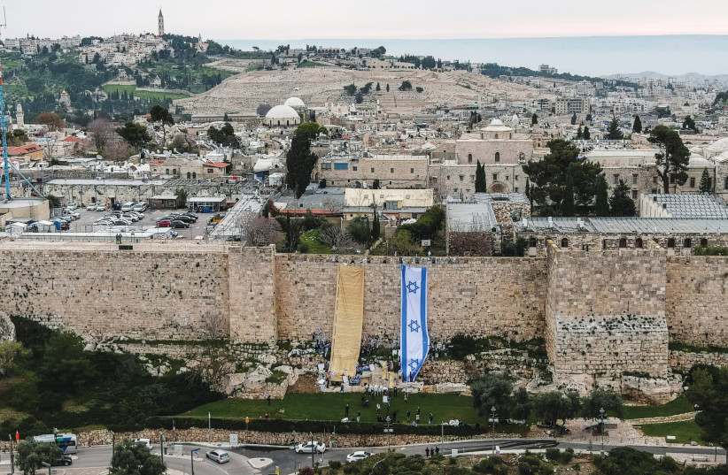  DRAPING COPIES of Israel’s flag and Declaration of Independence on Jerusalem’s Old City walls, in protest of judicial reform, in March. (photo credit: ILAN ROSENBERG/REUTERS)