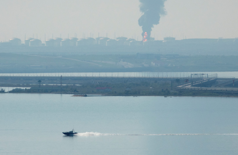  A view across the Kerch Strait shows a fuel depot on fire near the Crimean bridge in the village of Volna in Russia's Krasnodar region as seen from a coastline in Crimea, May 3, 2023. (photo credit: REUTERS/STRINGER)