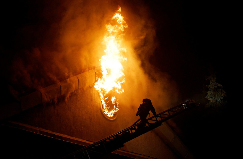 A firefighter climbs a ladder while extinguishing a fire in the university building following a reported shelling in the course of Russia-Ukraine conflict in Donetsk, Russian-controlled Ukraine, August 5, 2023. (photo credit: REUTERS/ALEXANDER ERMOCHENKO)
