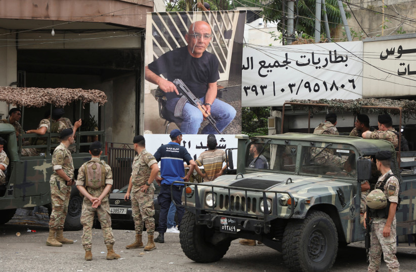  Lebanese army members stand near a poster of Fadi Bejjani who died during exchange of fire at the area where a truck was overturned the previous night, in the town of Kahaleh, Lebanon August 10, 2023. (photo credit: MOHAMED AZAKIR/REUTERS)