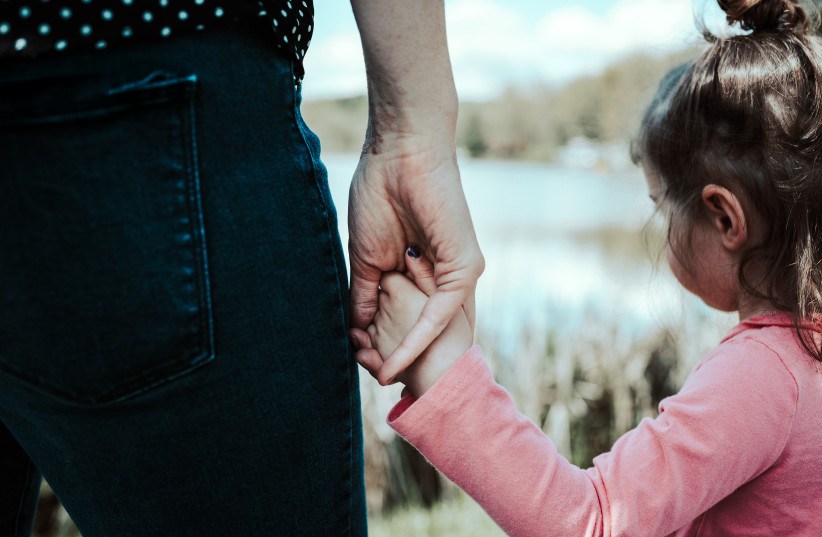  An illustrative photo of a young child holding someone's hand. (photo credit: Sandra Seitamaa/ Unsplash)