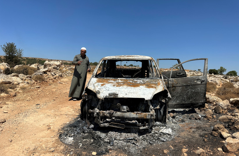Palestinian Saber Asaliyyeh reacts near a burned car after a confrontation with a group of Israeli settlers in Burka near Ramallah in the West Bank, August 9, 2023. (photo credit: REUTERS/ALI SAWAFTA)