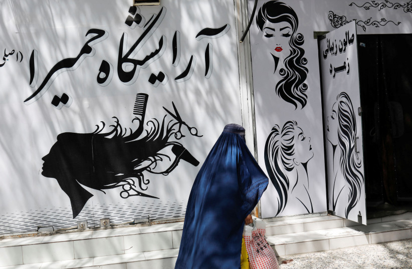  An Afghan woman walks past a beauty salon in Kabul, Afghanistan, July 6, 2023 (photo credit:  REUTERS/ALI KHARA)