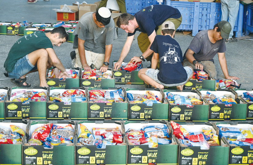  VOLUNTEERS PACK food for those in need, ahead of Rosh Hashanah and Sukkot in 2021, organized by the Horowitz family in memory of their son Eylon, who died during his military service. Change the lives of others for the better, the writer urges. (photo credit: MICHAEL GILADI/FLASH90)