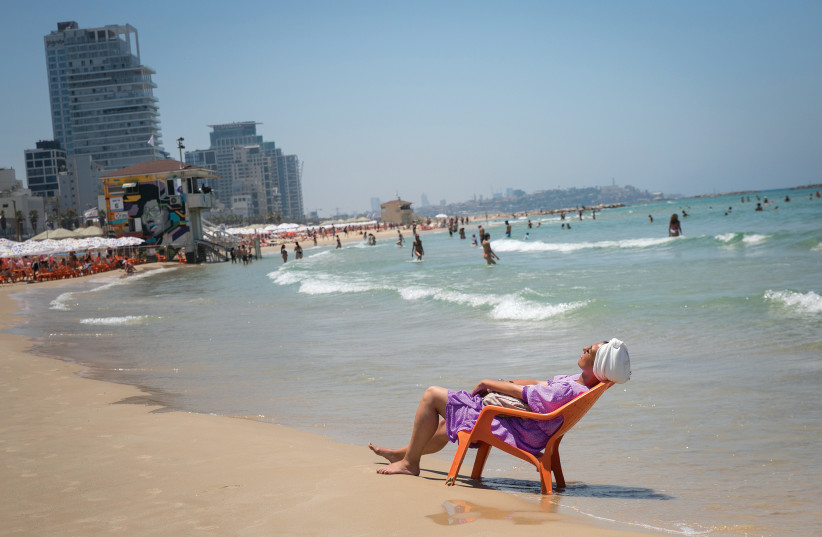  A WOMAN enjoys the beach in Tel Aviv last month as a heat wave hit the country.  (photo credit: MIRIAM ALSTER/FLASH90)