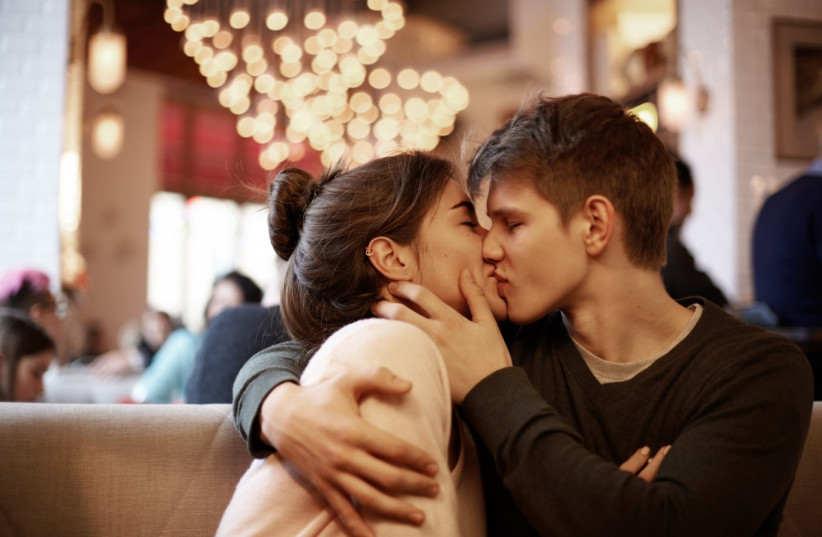 A couple kisses and holds each other in a cafe. (photo credit: PXHERE)