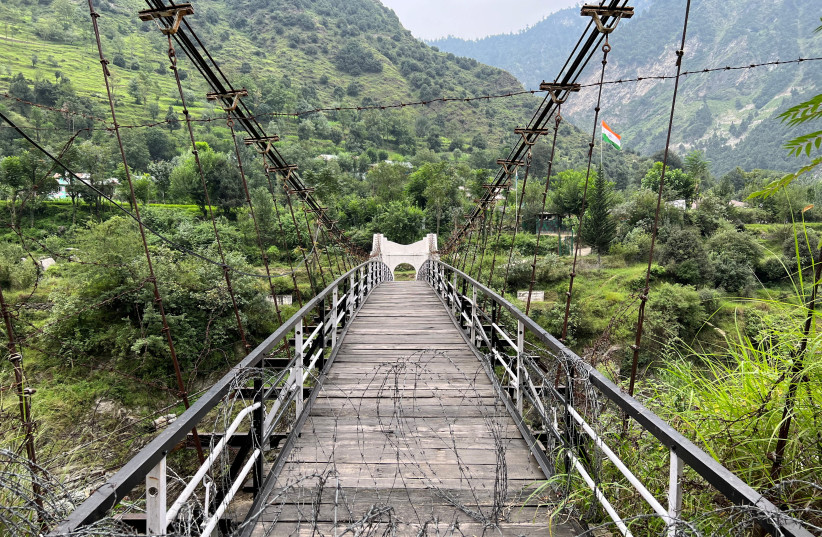   A general view of a bridge between Pakistan and India, closed since 2018, with an Indian flag in the background, in Chilehana, Pakistan-India crossing point in Kashmir, Pakistan, August 11, 2022 (photo credit: REUTERS/Gibran Peshimam)