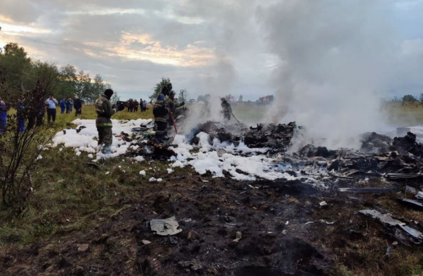 Firefighters work amid aircraft wreckage at an accident scene following the crash of a private jet in the Tver region, Russia, August 23, 2023.  (photo credit: Investigative Committee of Russia/Handout via REUTERS)