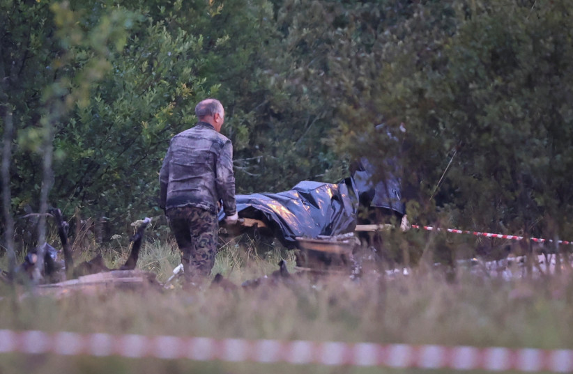 Emergency specialists carry a body bag near wreckages of the private jet linked to Wagner mercenary chief Yevgeny Prigozhin near the crash site in the Tver region, Russia, August 24, 2023 (photo credit: REUTERS/MARINA LYSTSEVA)