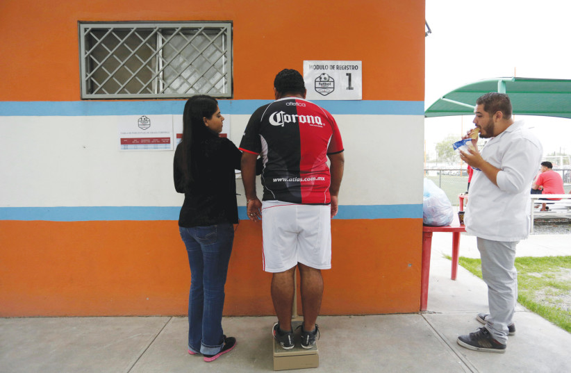  WEIGHING IN before a ‘Futbol de Peso’ match in a Mexican league for obese men who want to improve their health through soccer.  (photo credit: DANIEL BECERRIL/REUTERS)
