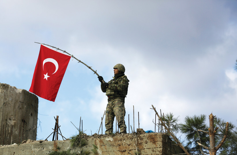  A TURKISH soldier waves a flag on Mount Barsaya, northeast of Afrin, Syria, in January 2018. (photo credit: Khalil Ashawi/Reuters)