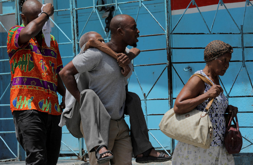  FILE PHOTO: A man carries an elderly man as they flee their neighbourhood Carrefour Feuilles after gangs took over, in Port-au-Prince, Haiti August 15, 2023. (photo credit: REUTERS/Ralph Tedy Erol/File Photo)