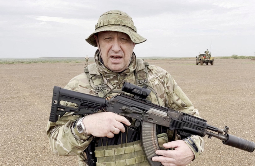   Yevgeny Prigozhin, chief of Russian private mercenary group Wagner, gives an address in camouflage and with a weapon in his hands in a desert area at an unknown location, in this still image taken from video possibly shot in Africa and published August 21, 2023. (photo credit:  Courtesy PMC Wagner via Telegram via REUTERS/File Photo)