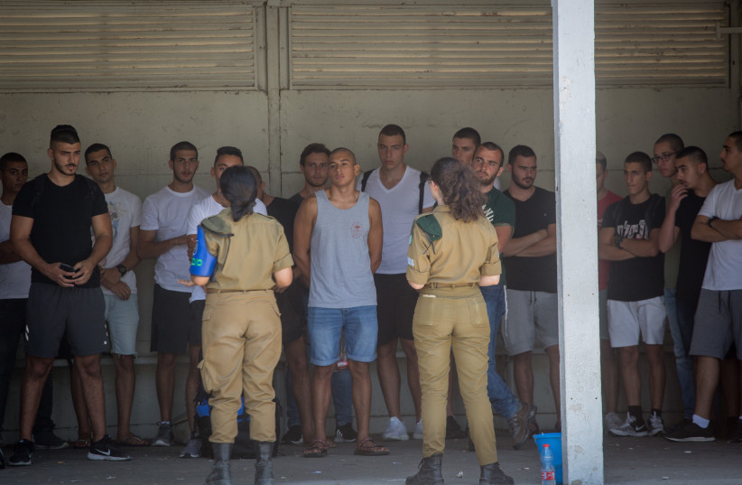 Young Israelis line up as they arrive to an Israeli army recruitment center at Tel Hashomer, outside of Tel Aviv on July 26, 2018 (photo credit: MIRIAM ALSTER/FLASH90)