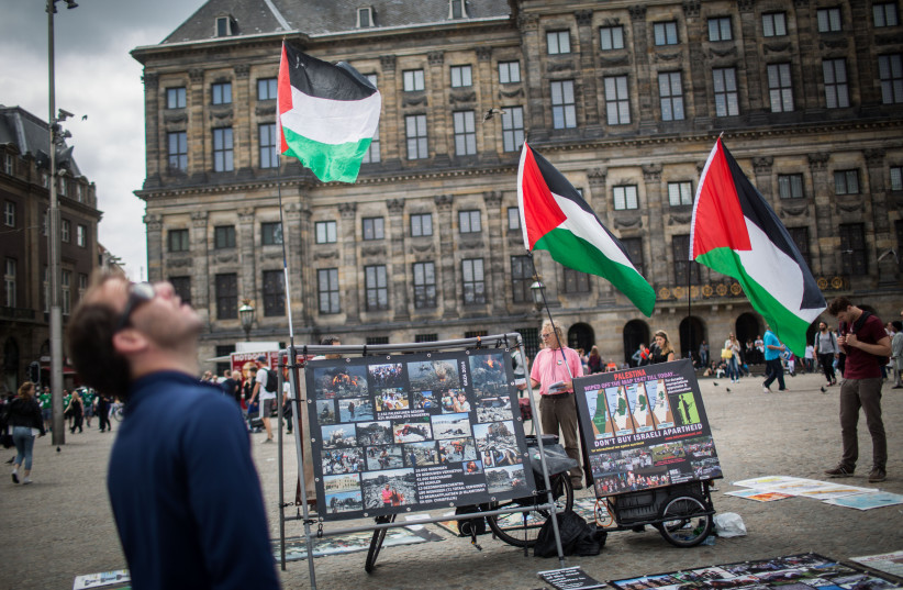  People look at a BDS stand with photos and Palestinian flags, calling to 'Free Palestine' at Dam Square in central Amterdam, Holland, on June 24, 2016. Photo by Hadas Parush/Flash90 (photo credit: HADAS PARUSH/FLASH90)