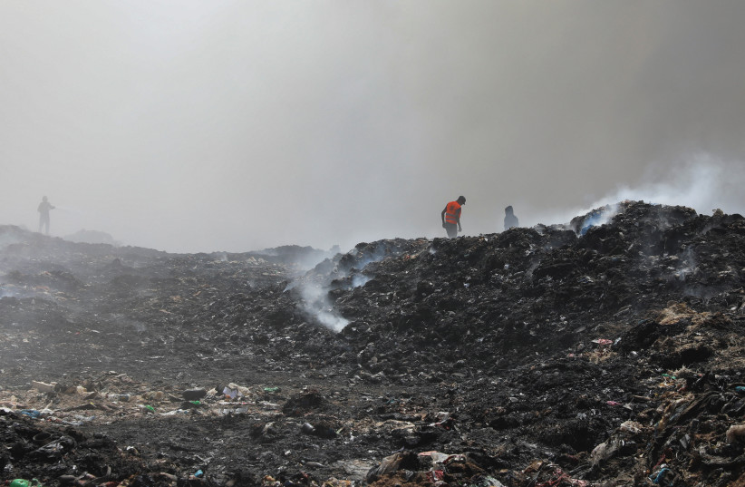  Palestinian firemen extinguish a fire at a landfill in Juhr al-Deek, southeast of Gaza City, September 3, 2023.  (photo credit: Reuters/Arafat Barbakh)