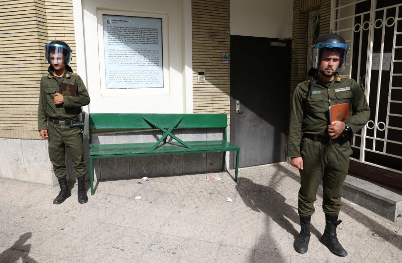 Police officers stand guard holding the Koran in their hands outside the Swedish Embassy, during a protest against a man who burned a copy of the book outside a mosque in the Swedish capital Stockholm, in Tehran, Iran July 3, 2023. (photo credit: Majid Asgaripour/West Asia News Agency/Reuters)