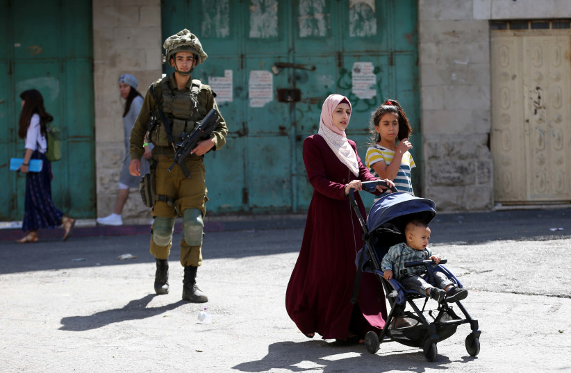  Israeli security forces guard as Jews (unseen) tour in the West Bank city of Hebron, during the Jewish holiday of Sukkot, September 22, 2021. (photo credit: WISAM HASHLAMOUN/FLASH90)